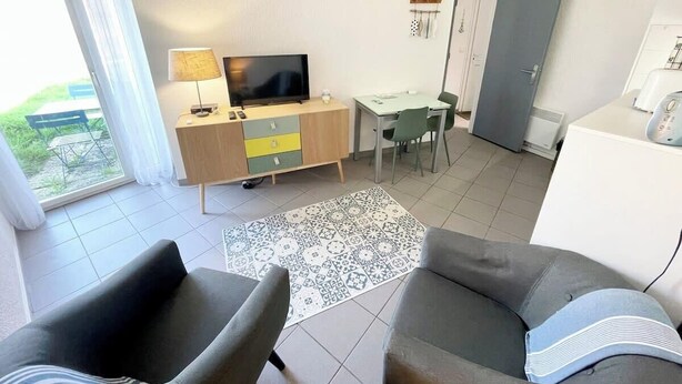 Een moderne woonkamer met een bank, een televisie, een eethoek en een keuken.