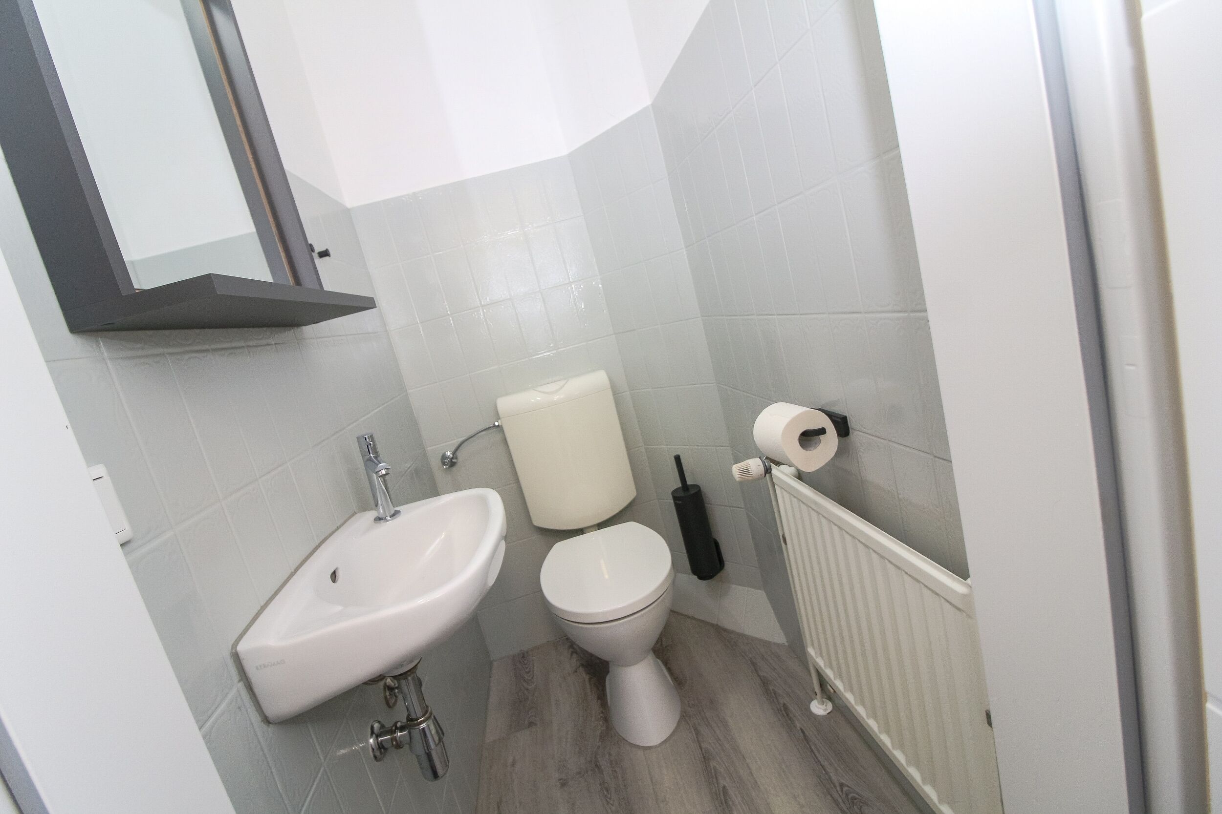 A bathroom with a white sink, toilet, and radiator.