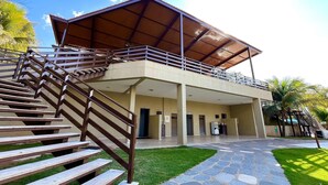 Ein Gebäude mit einer überdachten Außenfläche, einer Treppe, die zu einem Balkon führt, und einem Kiesweg.