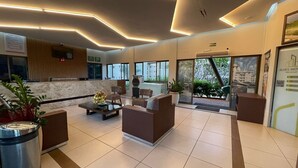 Eine moderne Lobby mit Empfangsschalter, Sitzgelegenheiten und großen Fenstern mit Blick ins Freie.