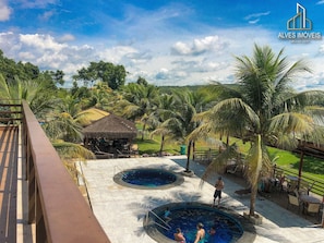 A resort with a pool area, palm trees, and a thatched-roof structure. - Aldeia do lago (Caldas Novas)