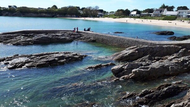 Une zone côtière caractérisée par des rivages rocheux, une eau claire et une plage de sable.