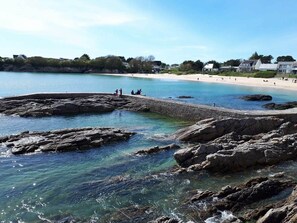 A coastal area with rocky shores, clear water, and a sandy beach.