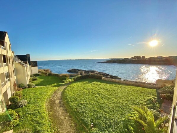 A coastal property with a grassy lawn, a pathway, and a view of the sea.