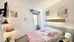 A neatly arranged bedroom with a bed, bedside tables, a lamp, and wall decorations.