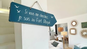 Un salon avec un panneau accroché au mur, un escalier et un coin repas.