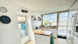 Une cuisine moderne avec des meubles blancs, un plan de travail en bois et une vue par la fenêtre.