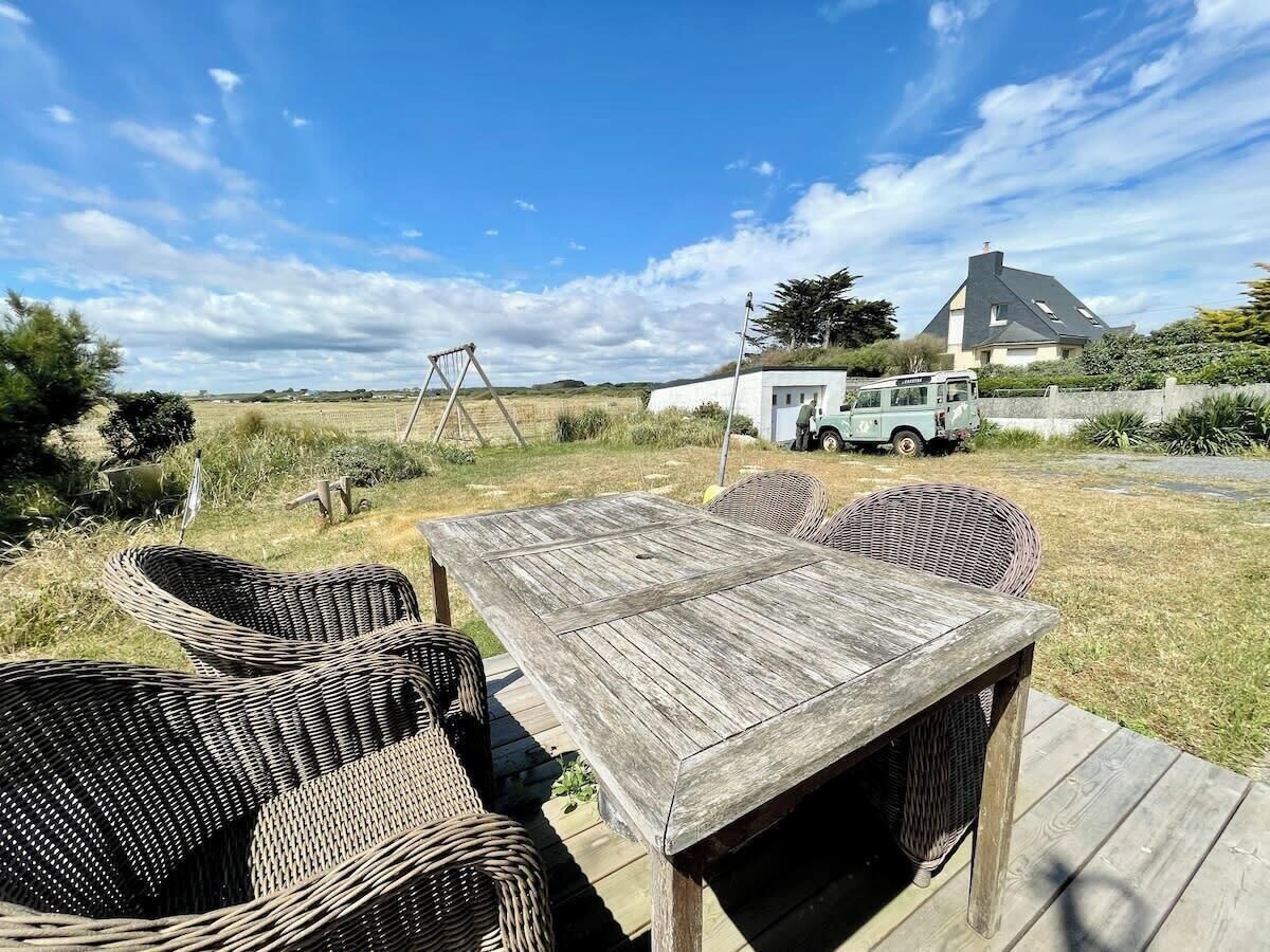 En træterrasse med fletstole, et bord og en gyngestol.