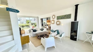 Un salon moderne avec une cheminée, des meubles blancs et une vue sur l’extérieur.