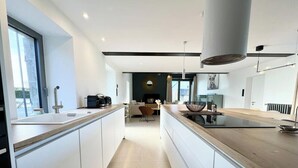 Een moderne keuken met witte kasten, een centraal eiland en uitzicht op de eethoek.