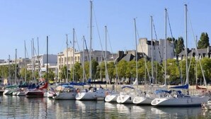 Un port de plaisance où sont amarrés de nombreux voiliers, entouré de bâtiments et d’arbres.
