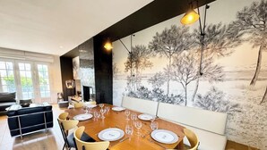 A dining area with a long wooden table set for six, surrounded by cushioned chairs. - Luxury Magnifique Villa d architecte Cocooning (Larmor-Plage)