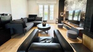 A modern living room with a sofa set, a coffee table, and a flat-screen TV mounted on the wall. - Luxury Magnifique Villa d architecte Cocooning (Larmor-Plage)