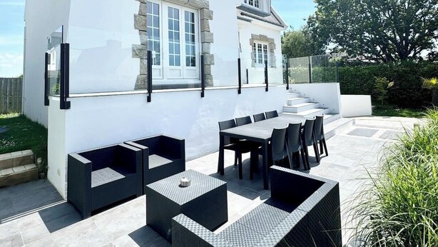 A modern house with a white exterior, stone accents, and a patio with outdoor furniture. - Luxury Magnifique Villa d architecte Cocooning (Larmor-Plage)