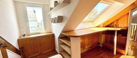 Un dormitorio loft moderno y compacto con techo inclinado, mobiliario de madera y tragaluces.