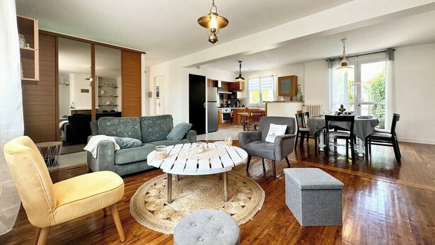 A spacious living room with a round coffee table, sofas, and a dining area with a table and chairs.