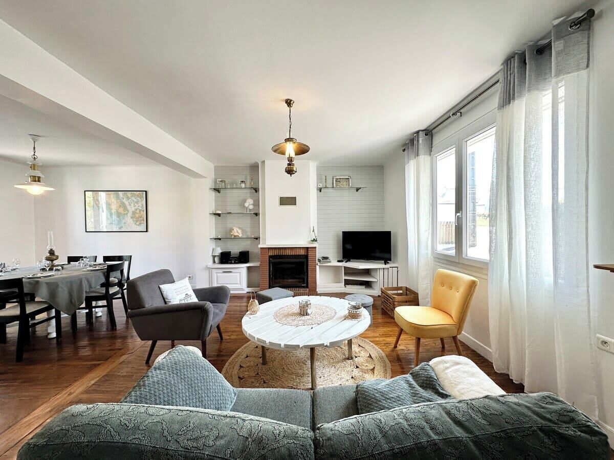 Ein modernes Wohnzimmer mit einem runden Couchtisch, Sofas, einem Fernseher und einem Kamin.