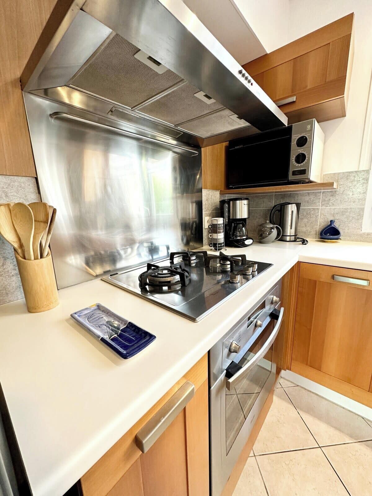 A modern kitchen with stainless steel appliances, wooden cabinets, and a white countertop.