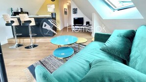 Una sala moderna con un sofá color turquesa, una mesita de centro y un comedor con taburetes de bar.