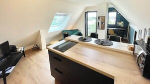 Un moderno apartamento tipo loft con cocina que incluye una isla grande, una mesa de comedor y vistas de la ciudad a través de un tragaluz.