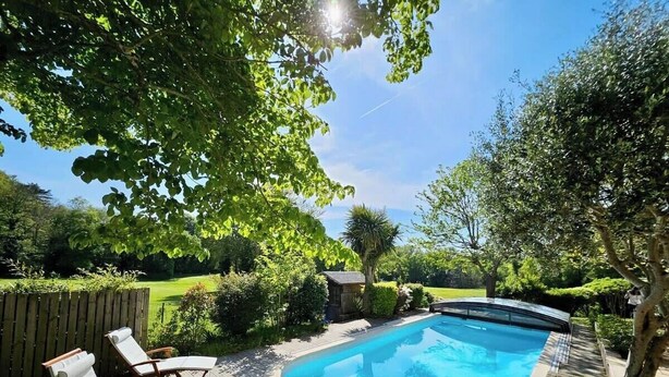 A backyard with a swimming pool, surrounded by a wooden deck and lounge chairs.
