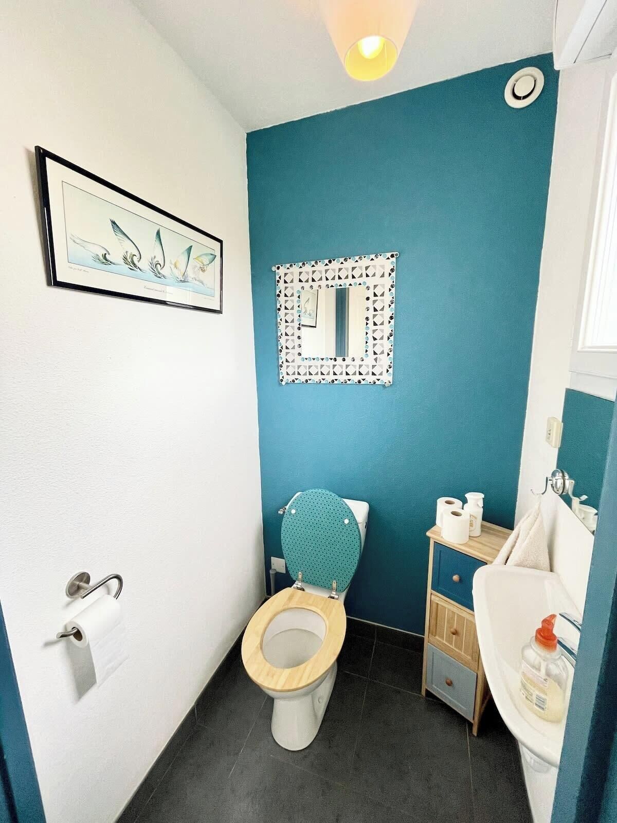 A bathroom with a toilet, sink, and a mirror.