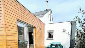 Una terraza de madera con una mesa de picnic, una puerta corrediza de vidrio y una chimenea.