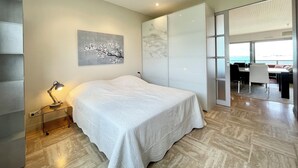 A modern bedroom with a large bed, a desk, and a view of the sea. - Luxury T3 standing 2 - Vue mer exceptionnelle 180° (Larmor-Plage)
