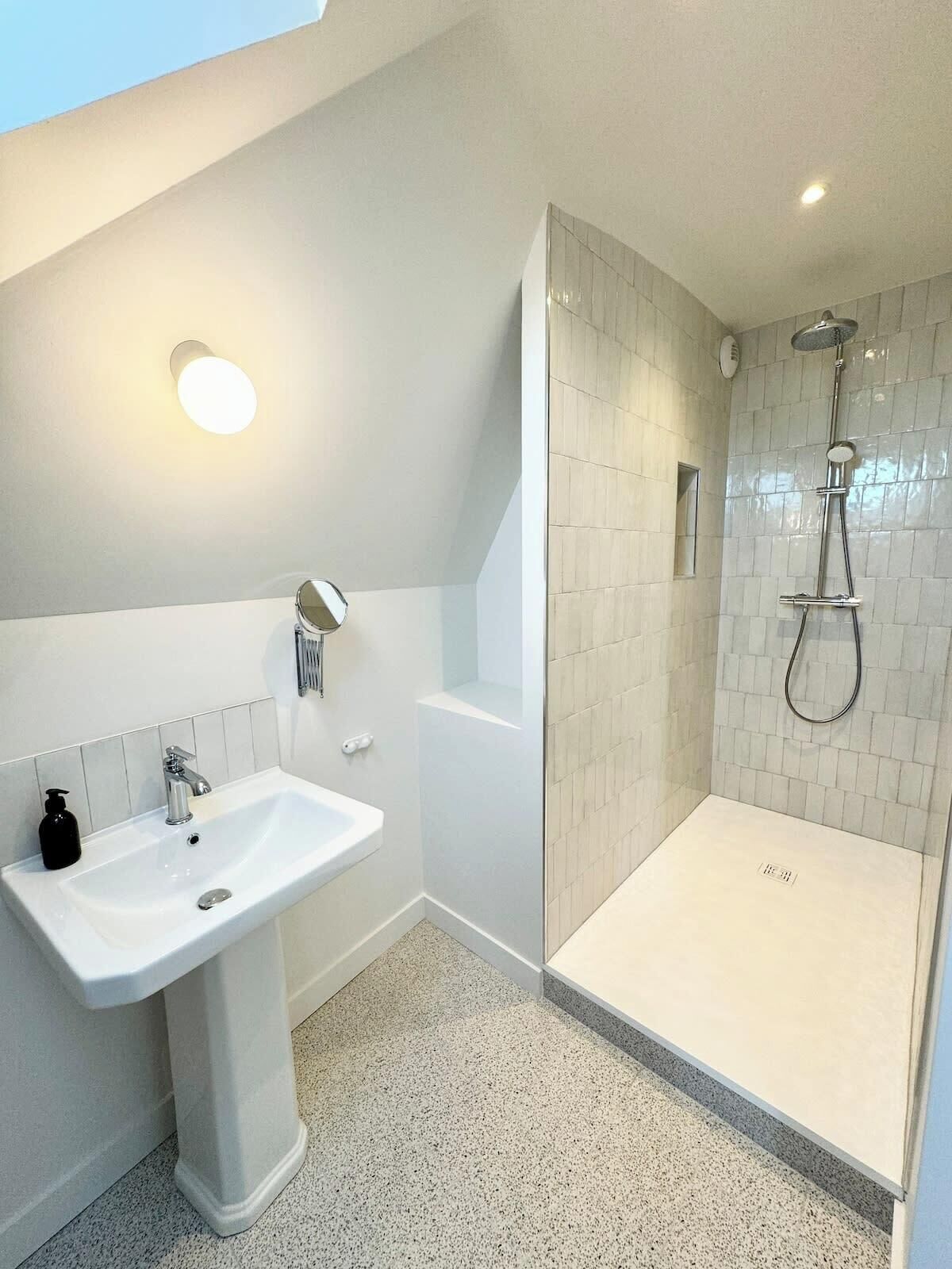A modern bathroom with a white sink, a bathtub, and a glass-enclosed shower area.