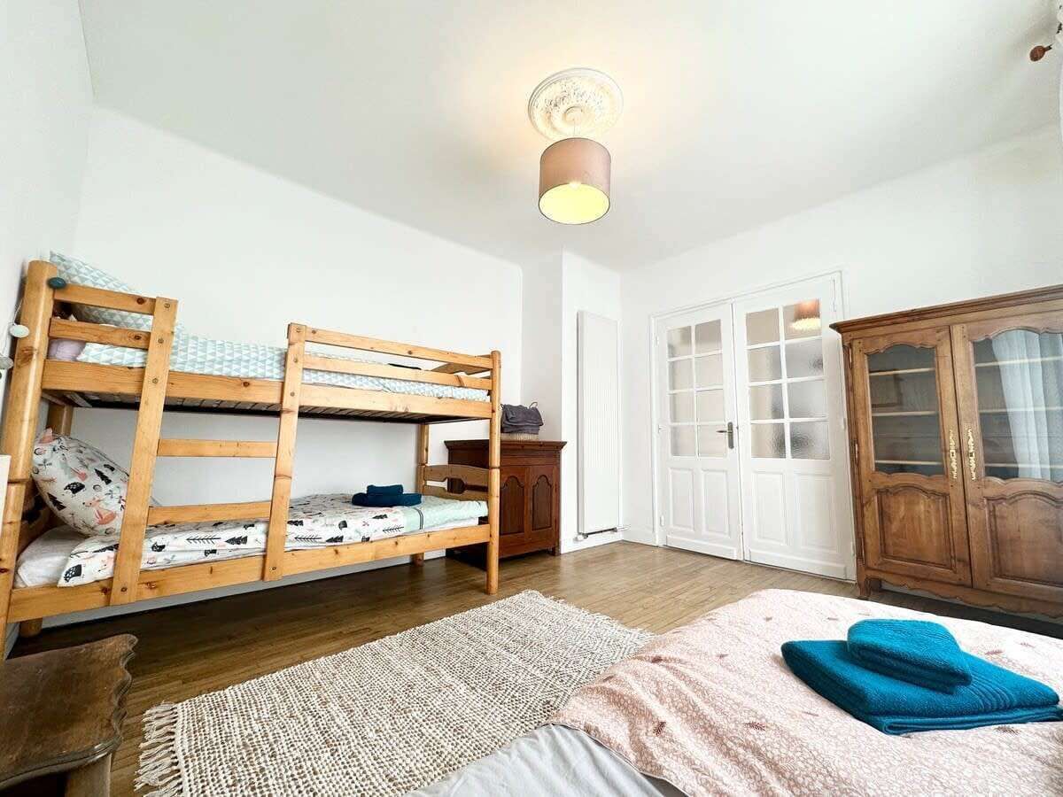 Une pièce avec deux lits superposés, une armoire en bois et une porte dont les panneaux sont en verre dépoli.