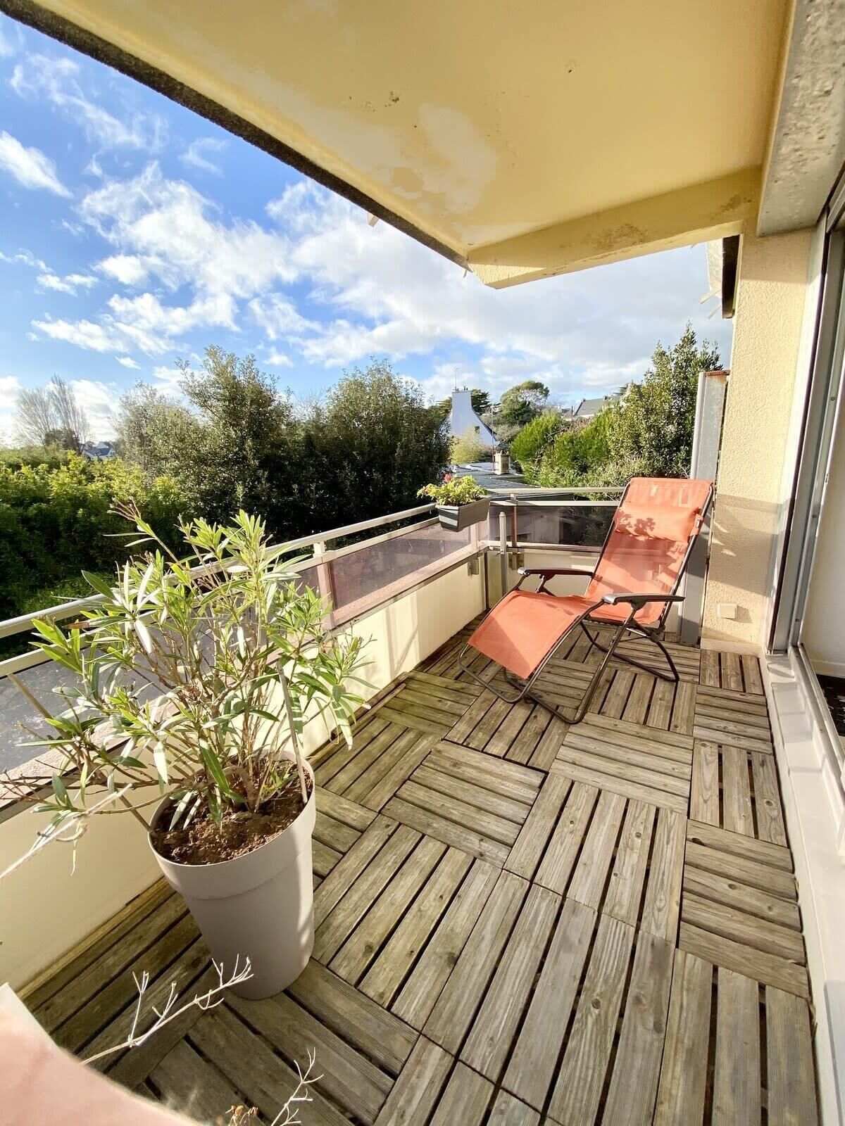 A wooden deck with a potted plant and a single orange chair.