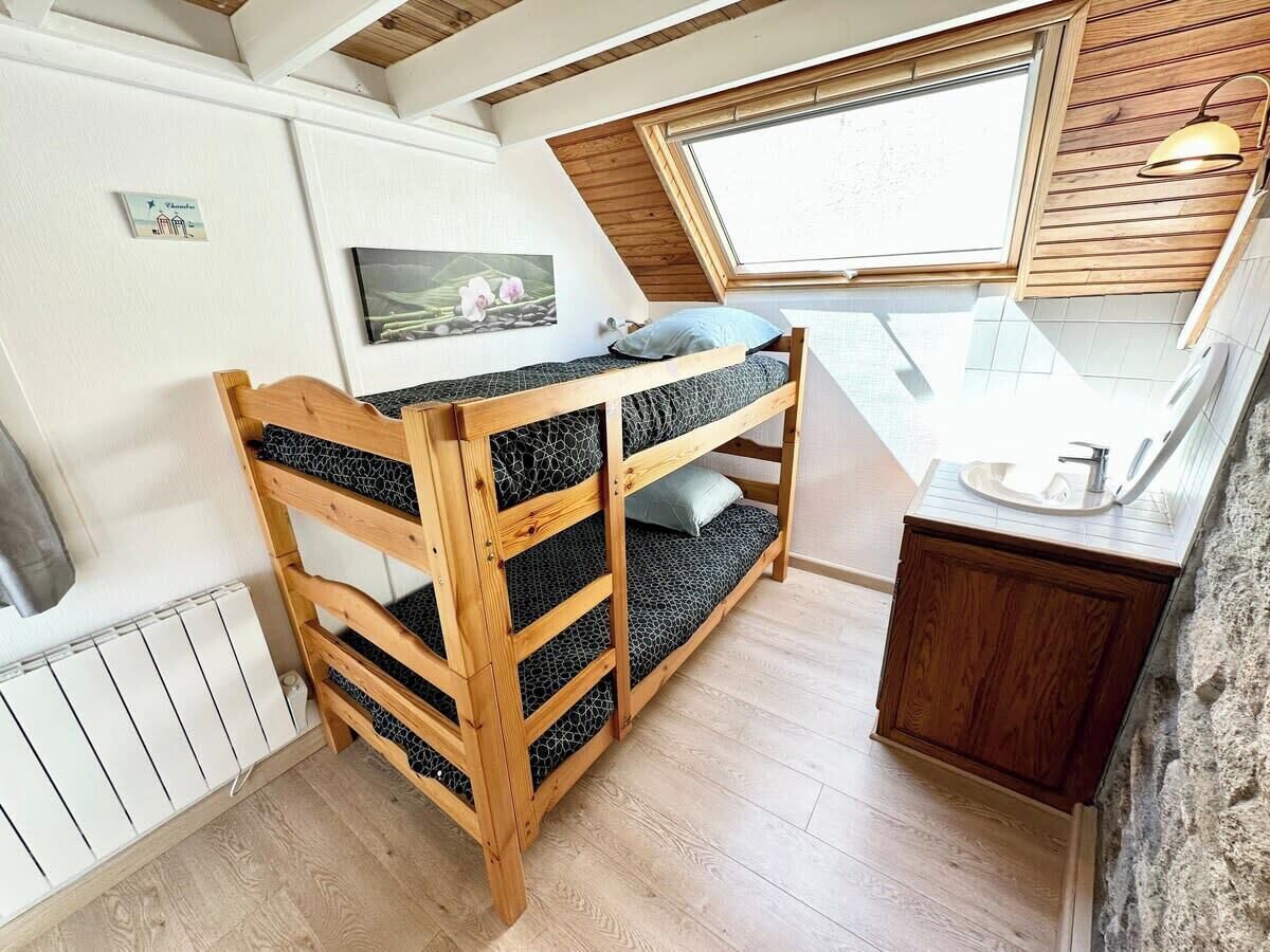 Habitación compacta con literas, una kitchenette pequeña y un tragaluz.