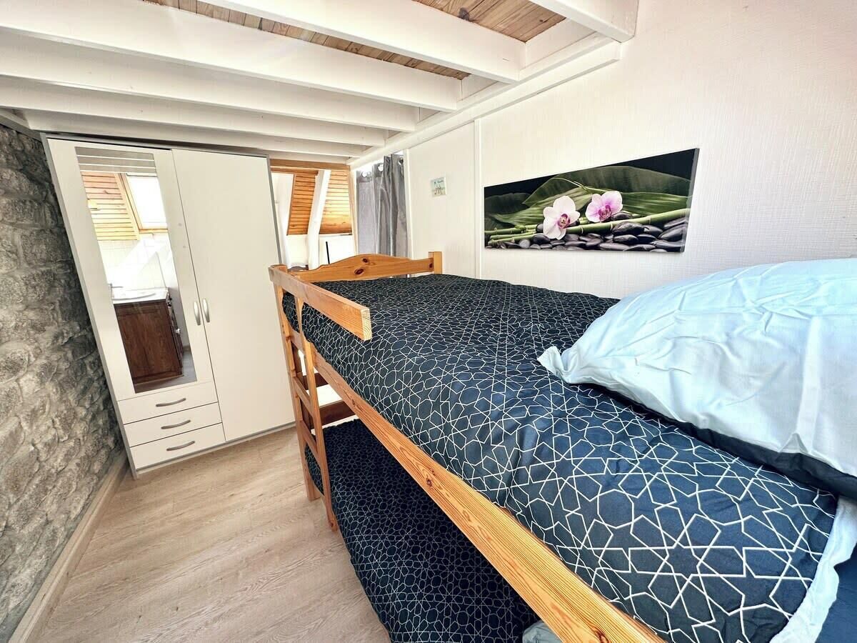 Un dormitorio con una litera, un armario de madera y un cuadro de flores colgado en la pared.