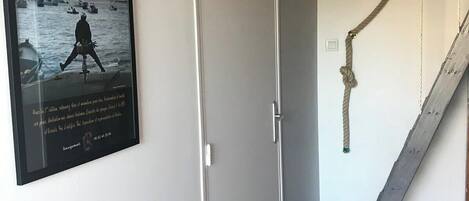 A room with a white door, a poster on the wall, and a rope swing.