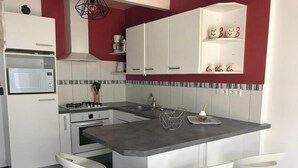 Una cocina moderna con armarios blancos, microondas integrado, cocina a gas y una isla central con taburetes de bar.