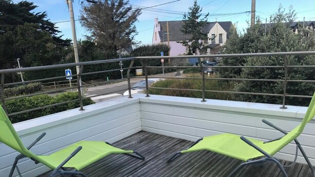 Una terraza al aire libre con dos sillas verdes y una barandilla.