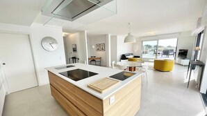 A modern kitchen with a central island, built-in appliances, and a large window providing a view of the outdoors.