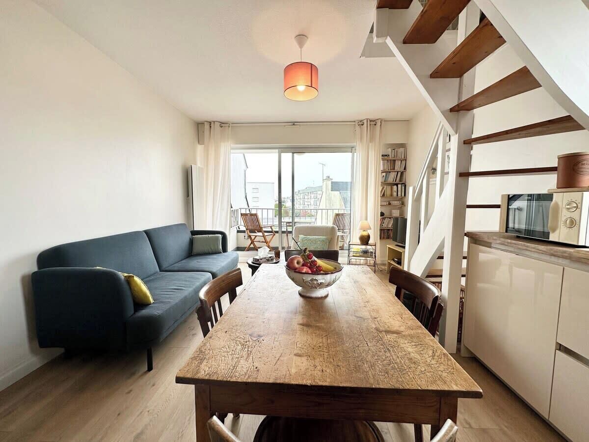 En moderne opholdsstue med spisebord, sofa og et køkkenområde.