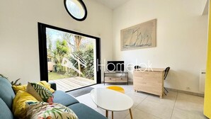 Una sala moderna con un sofá, una mesita blanca y un mueble de madera.