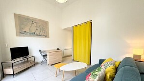 Una sala de estar moderna con un sofá, un televisor, una mesita y un cuadro en la pared.