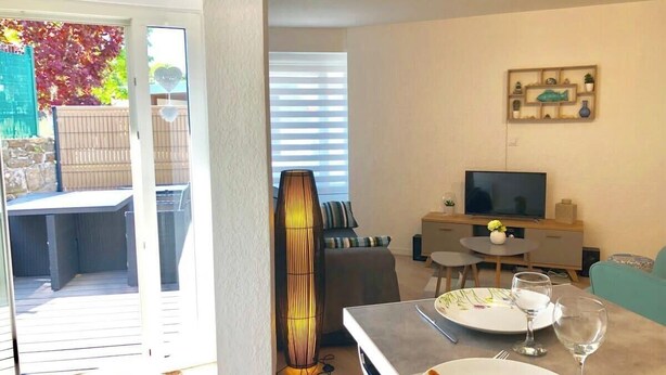 Een moderne woonkamer met een eethoek, een bank, een televisie en een grote vloerlamp.
