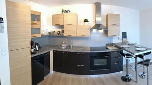 Een moderne keuken met een rond eiland, ingebouwde apparatuur en een klok aan de muur.
