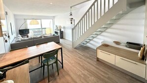 Un espace de vie moderne comprenant une table à manger en bois, un canapé et un escalier.