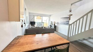 Une cuisine moderne avec une table et des chaises en bois, un banc intégré et un escalier menant à un balcon.