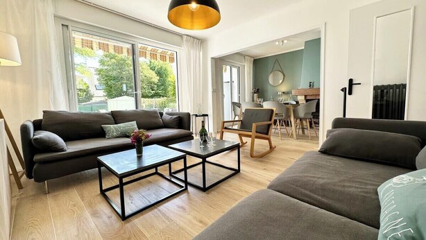 A modern living room with a sofa, coffee table, and a dining area with chairs.