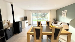 Un salon moderne comprenant un coin repas, un poêle à bois noir, un canapé et un téléviseur.