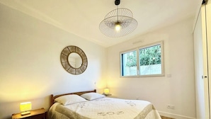 Une chambre à coucher avec un lit, des lampes de chevet, un miroir rond et une fenêtre.