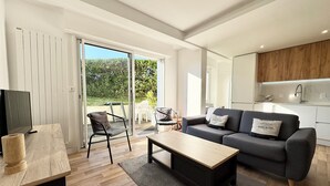 Ein modernes Wohnzimmer mit einer Couch, einem Couchtisch und einem Fernseher auf einem Holztisch.