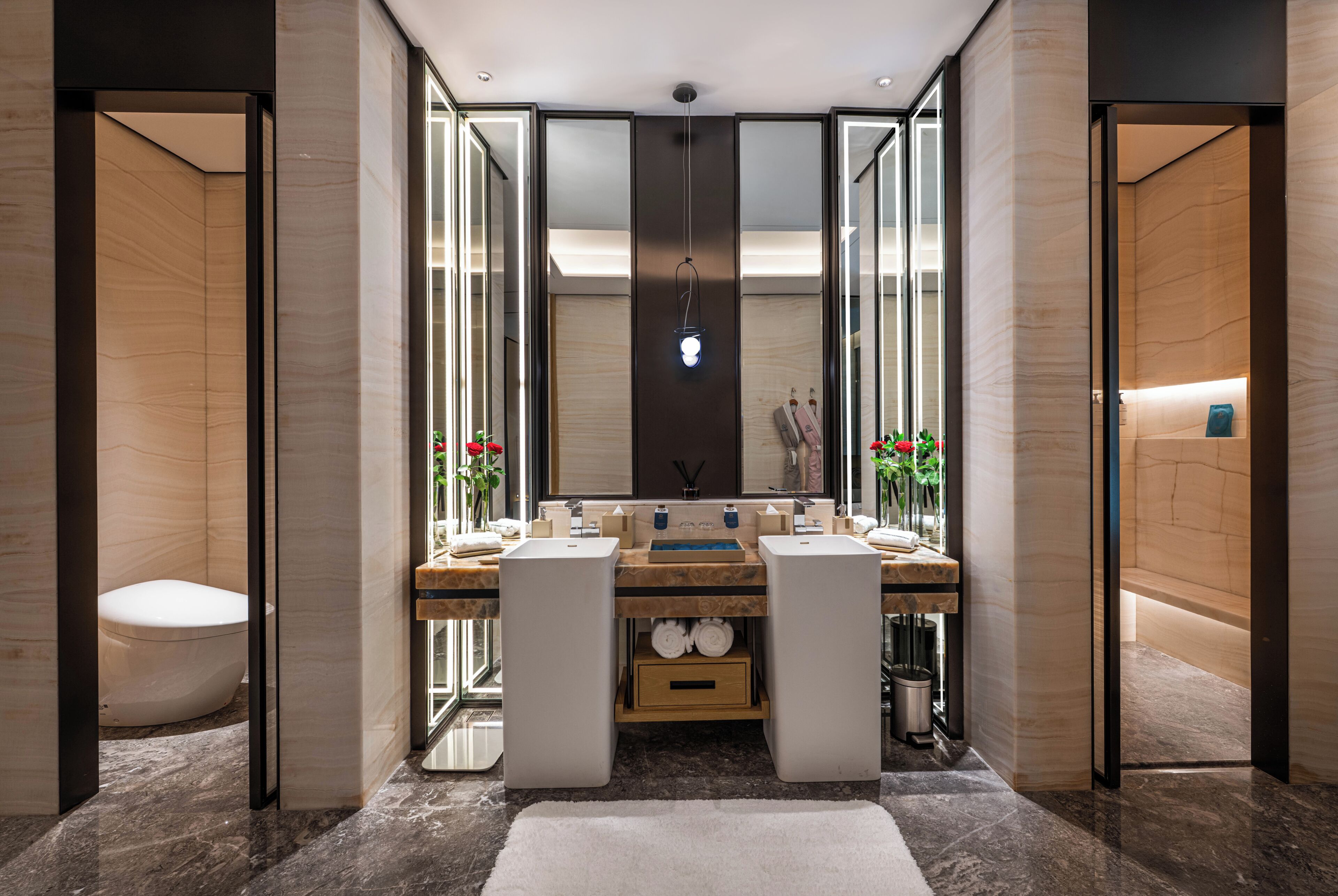 A modern bathroom with a large mirror, two sinks, and a toilet.