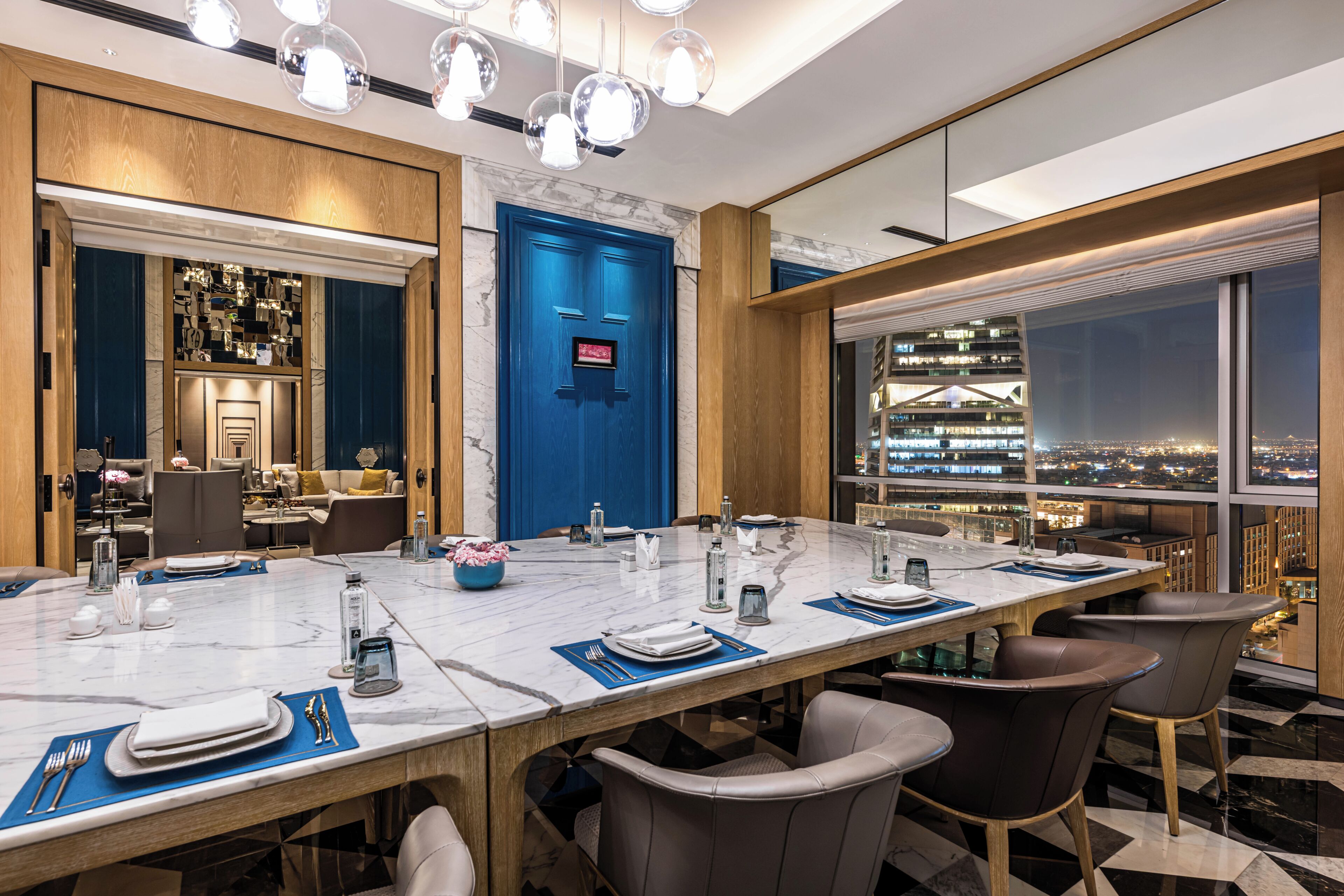 Un salón de conferencias moderno en un hotel, con una mesa de mármol, sillas de cuero y vista a la ciudad.